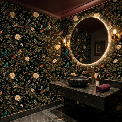 A modern bathroom features dark marble countertops, a bowl sink, gold fixtures, a lit circular mirror, and dark floral wallpaper.