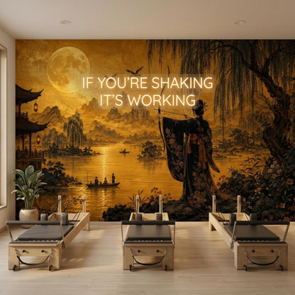 A room with Pilates reformers and a wall mural depicting a golden Japanese landscape with a giant moon and archer.