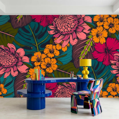 A home office features a blue desk, a geometric patterned chair, and a yellow lamp against a dark tropical floral wallpaper wall.