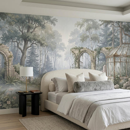 A bed with white linens and grey decorative pillows is positioned against the misty woodland wall mural.