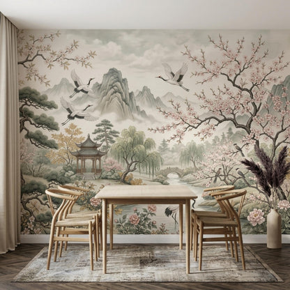 A dining area with a light wood table and chairs set on a patterned rug, against a backdrop of a large wall mural depicting a serene oriental landscape.