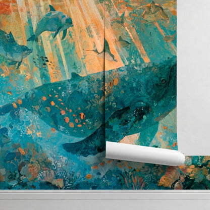 A close-up of a wall mural featuring a blue whale and dolphins, with a roll of the same wallpaper standing upright against the wall.