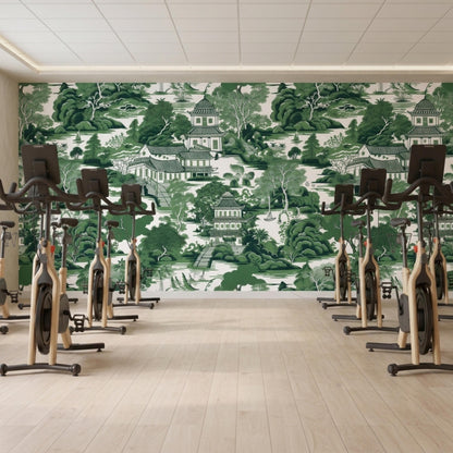 A fitness room features multiple stationary bikes lined up in front of a green chinoiserie wallpaper wall.