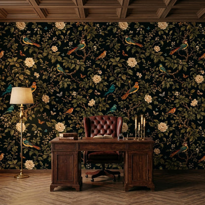 A dark wooden executive desk with a tufted leather chair sits in front of dark floral wallpaper and a tall floor lamp.