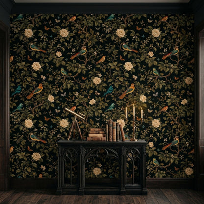 A dark floral Chinoiserie wallpaper covers a wall behind a black console table holding books, a small telescope, and lit candles.