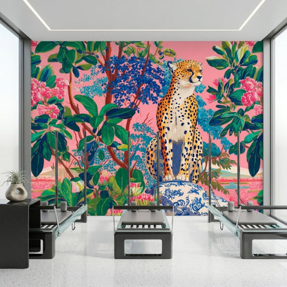 A wellness room has three pilates reformer machines positioned in front of a pink leopard jungle wallpaper mural.