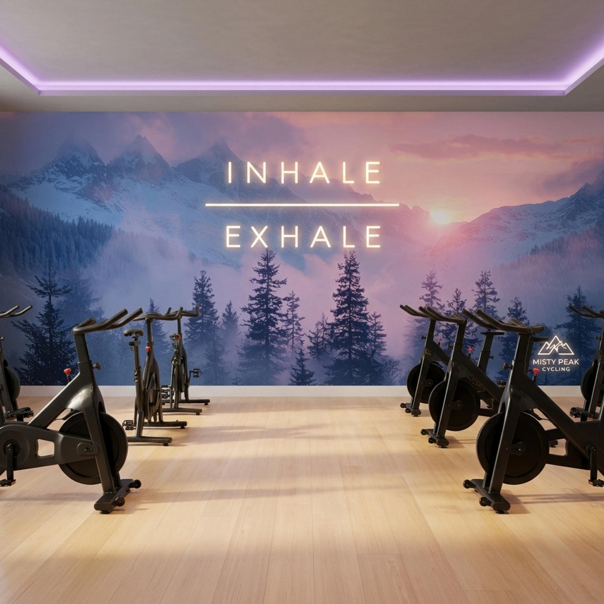 Indoor cycling studio with stationary bikes lined up against a misty mountain wall mural featuring illuminated neon text.