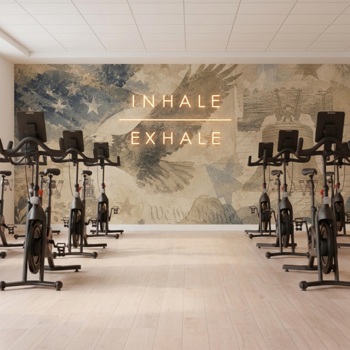 An exercise studio features rows of black spin bikes and glowing text on a patriotic vintage-style wall mural.