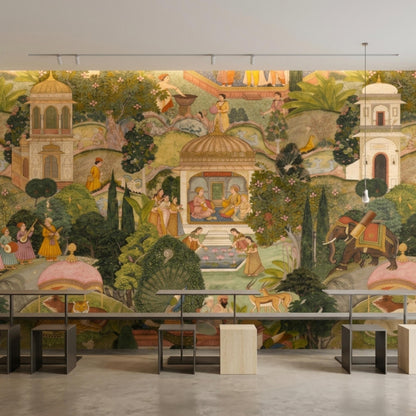 A panoramic Mughal art wallpaper features a detailed nature scene with figures and animals, set behind sleek metal and wood furniture.