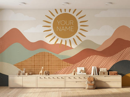 A long wooden low storage cabinet sits against a wall mural featuring layered abstract mountains and a sun with the text YOUR NAME.