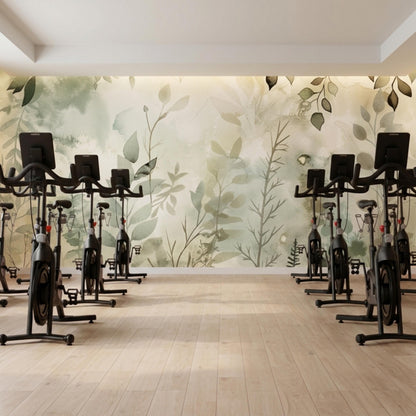 A fitness studio with rows of stationary exercise bikes on a wooden floor in front of a sage green botanical wall mural.