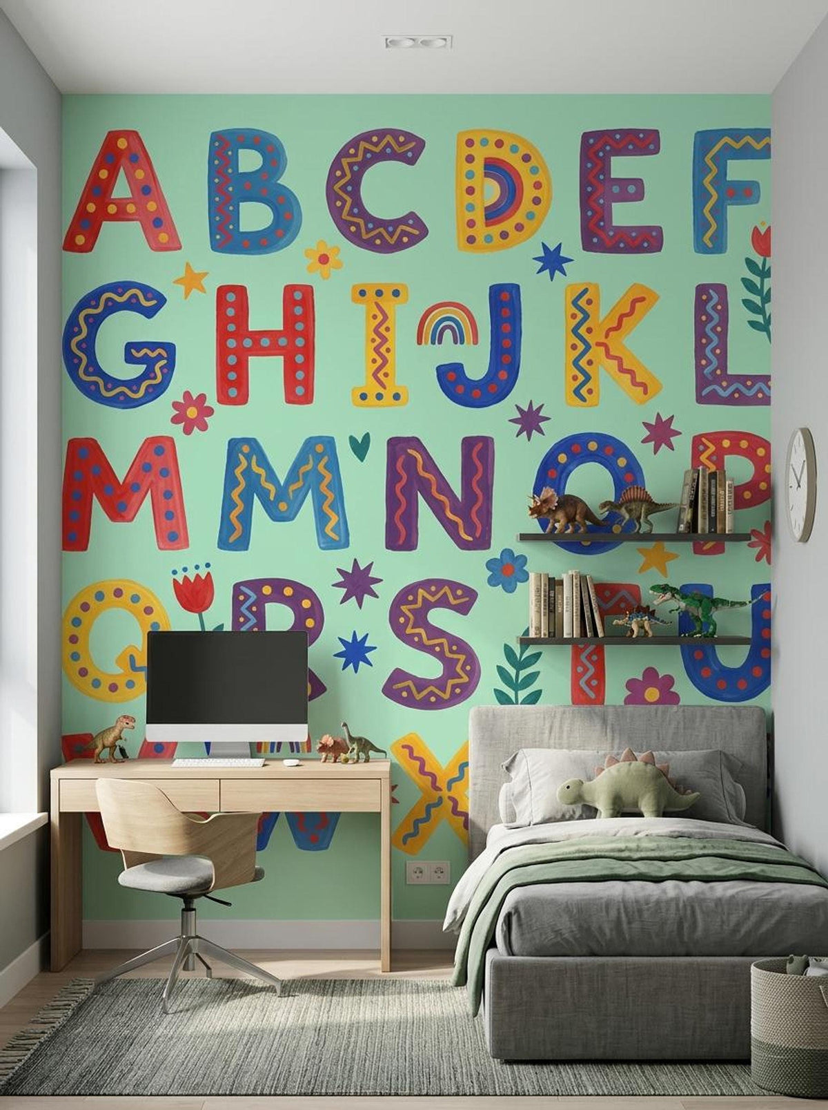 A boy's bedroom featuring a gray upholstered bed and a wooden desk set against a mint green wall with a folk art alphabet mural.