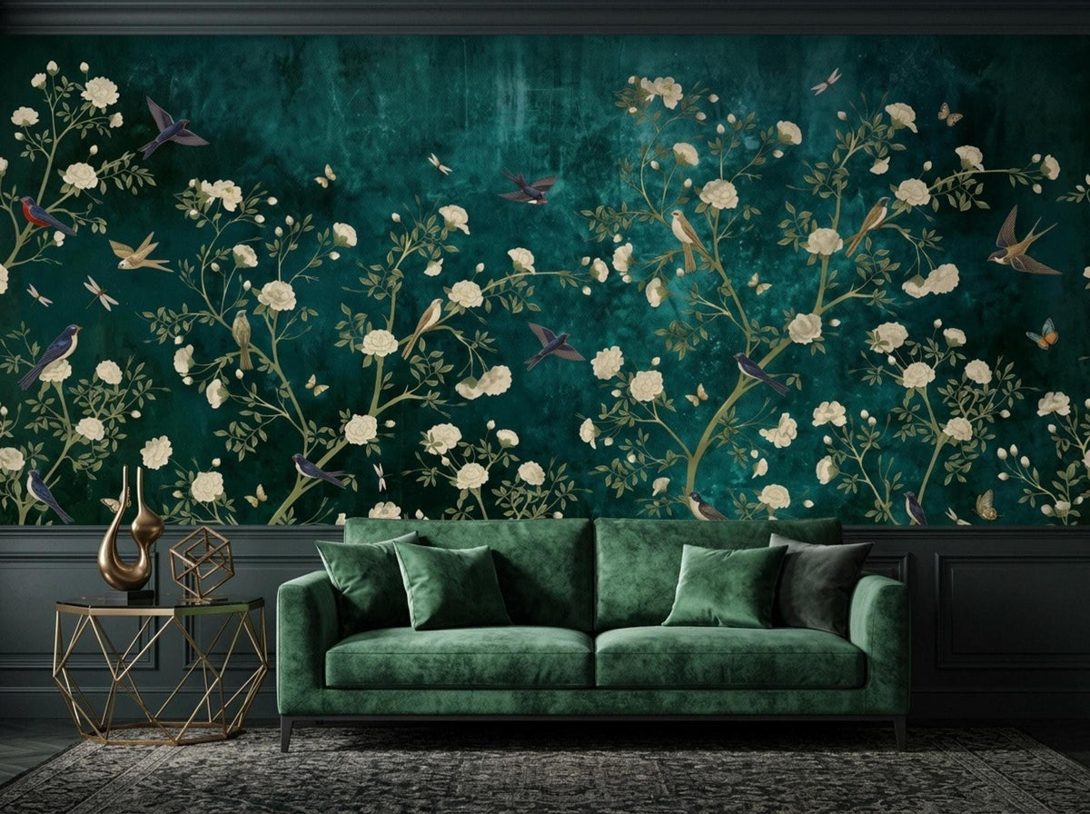 A green velvet sofa stands in a living room against a dark teal wall mural featuring white flowers and flying birds.