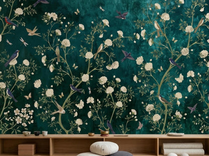 A wooden console table sits against an emerald chinoiserie floral wallpaper mural with painted birds and branches.