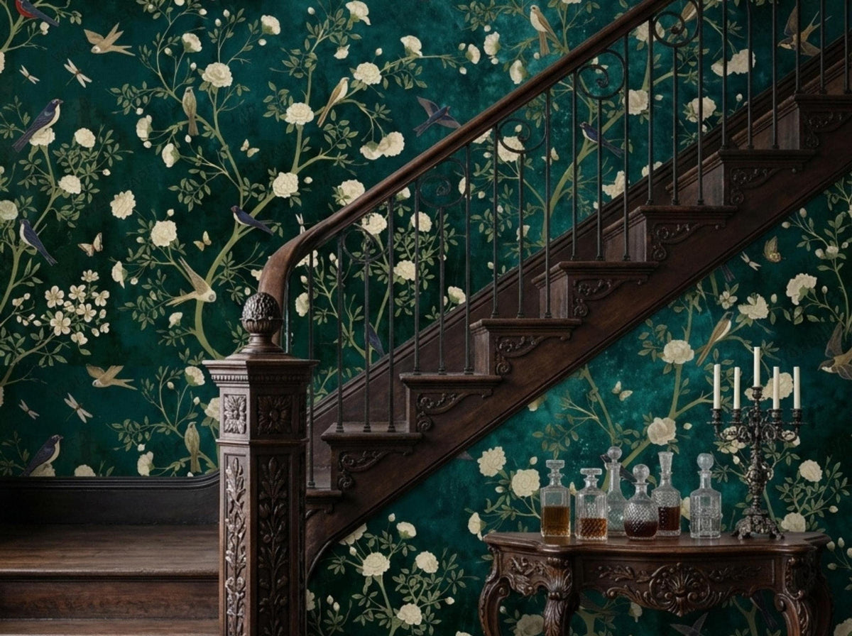 A wooden staircase with ornate dark railings and a small table with glass decanters are set against a dark green botanical mural.