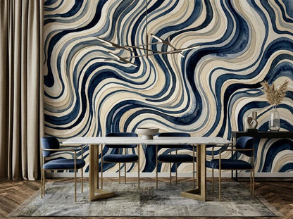 A dining room with a white marble table, gold-framed blue velvet chairs, and a large wall covered in a blue and beige wavy watercolor wallpaper mural.