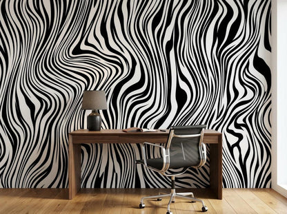 A wooden desk with a lamp and rolling chair is placed against a dramatic black and white abstract striped wall.