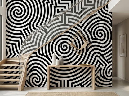 A modern hallway features a black and white spiral pattern wallpaper mural next to a wooden staircase and console table.