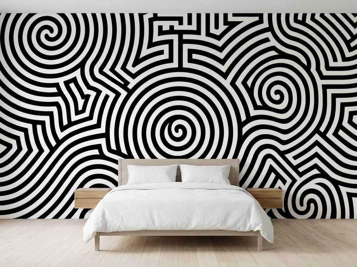 A bedroom features a wooden bed with white linens placed against a wall covered in a black and white op art spiral mural.