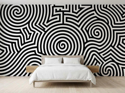 A bedroom features a wooden bed with white linens placed against a wall covered in a black and white op art spiral mural.