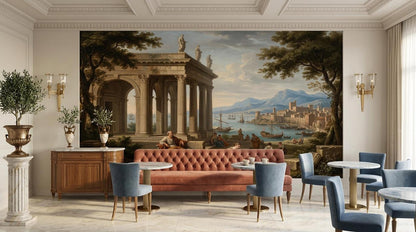 A neoclassical Mediterranean landscape mural spans a wall above a salmon-pink sofa, flanked by small dining tables and chairs in a bright, ornate room.