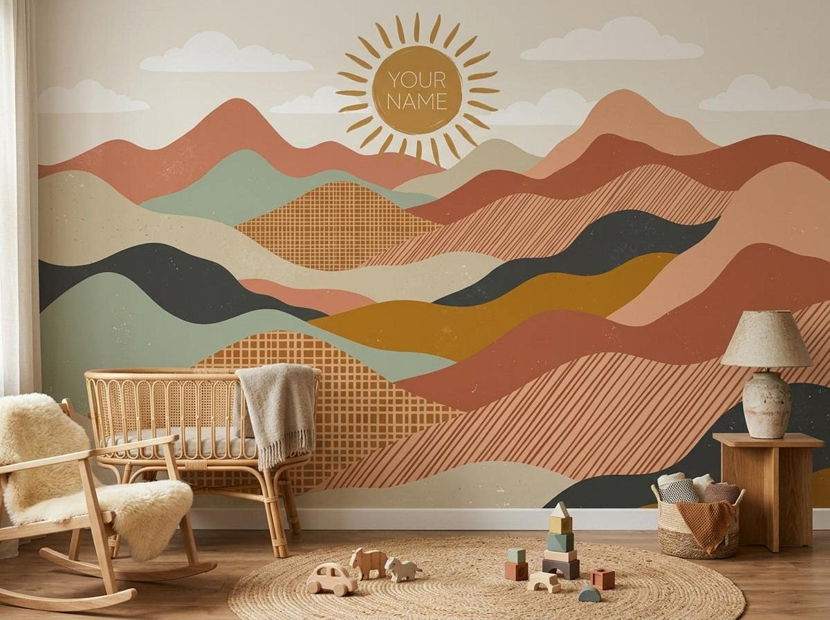 A nursery with a rocking chair, wicker crib, and a terracotta boho mountain and sun wall mural that includes the text YOUR NAME.