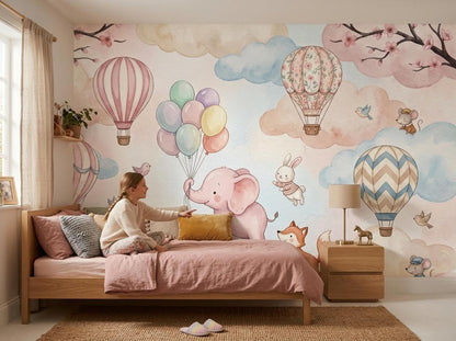 A young girl sits on a pink-bedded wooden frame bed pointing at the watercolor mural covering the wall behind it.