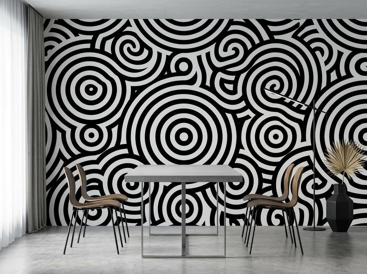 A dining space with a rectangular table and chairs positioned against a wall covered in black and white concentric circle wallpaper.