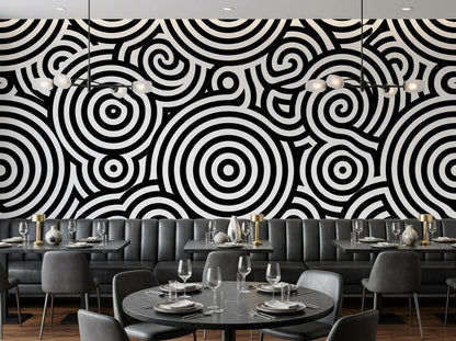 A restaurant setting with dining tables and gray seating against a striking black and white patterned feature wall.
