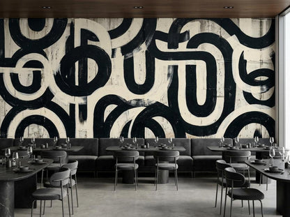 A modern restaurant setup with gray banquette seating, black tables, and a large abstract black and white brushstroke feature wall.