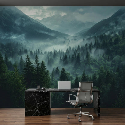 An office setup with a black marble desk, a silver chair, and a laptop against a foggy mountain and pine forest wall mural.