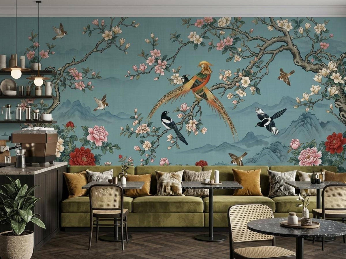 The teal chinoiserie wallpaper mural installed behind a restaurant seating area with olive green booths and small tables.