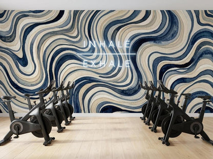 A row of exercise bikes faces a blue wavy watercolor mural with the text inhale exhale overlaying the wall.