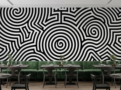 A restaurant setting showcases a bold black and white abstract spiral wall mural behind green velvet booths and tables.