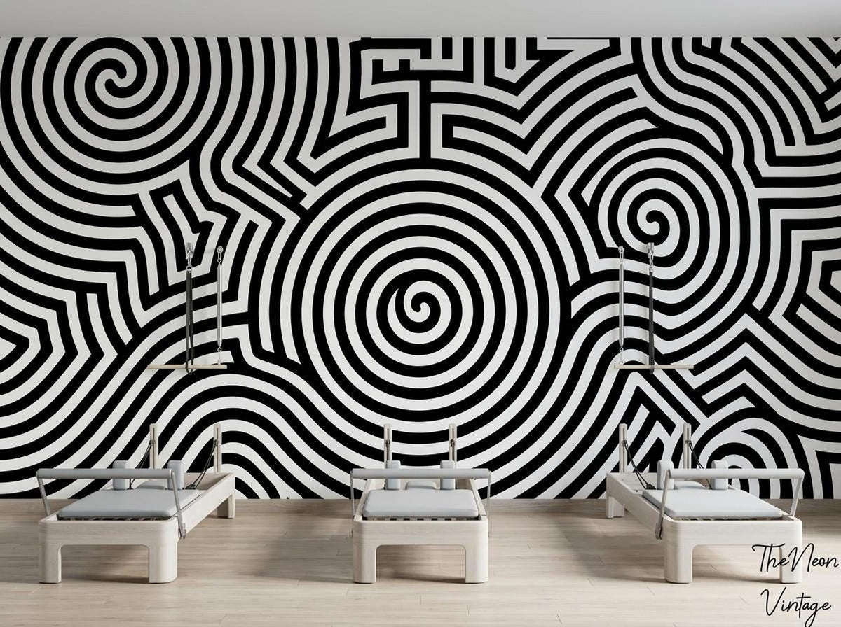 A fitness studio features three Pilates reformer machines positioned in front of a striking black and white spiral wallpaper mural.