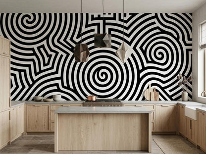 A contemporary kitchen displays light wood cabinetry and counters below a large black and white geometric spiral wall mural.