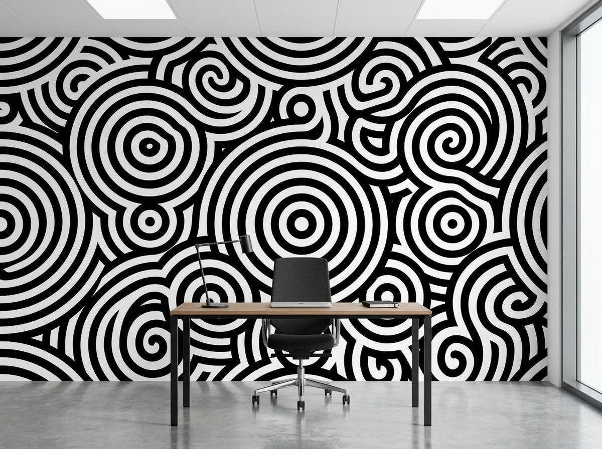 An office setup with a desk and chair centered in front of a bold black and white optical illusion wallpaper mural.