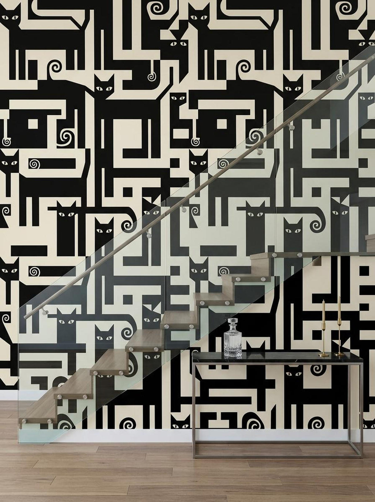 A wooden staircase with a glass railing stands in front of a wall featuring black and cream geometric wallpaper with repeating cat motifs.