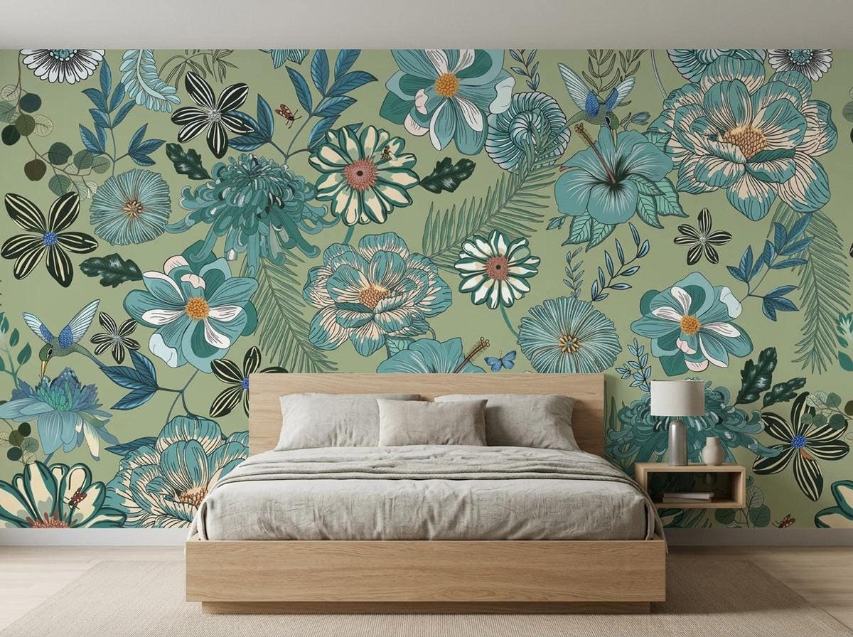 A wooden bed with grey bedding is placed in front of a sage green botanical wallpaper mural featuring large blue flowers and hummingbirds.