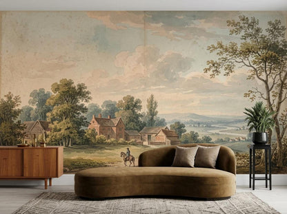 A curved brown velvet sofa positioned against a large vintage landscape wall mural showing rural farm buildings and trees.