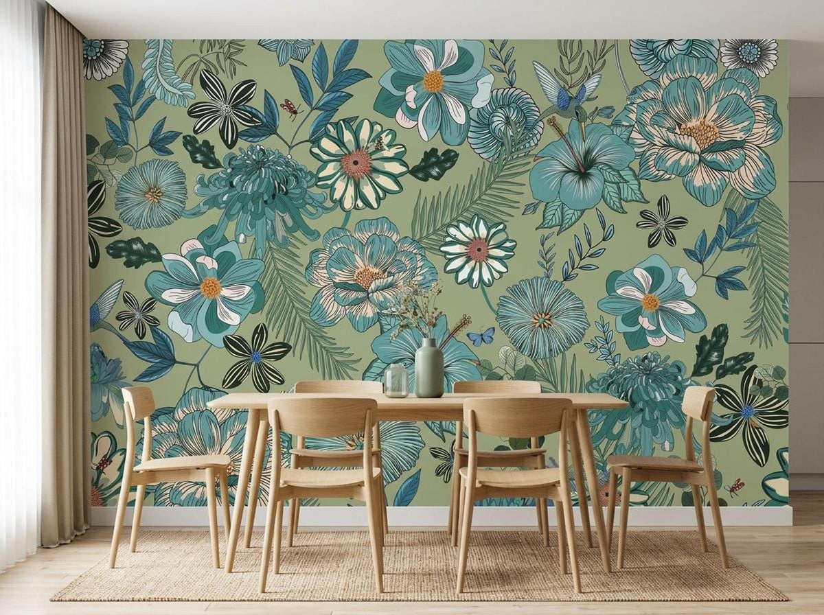 A wooden dining table and four chairs sit on a jute rug in front of a sage green botanical wallpaper mural with vintage blue flowers.