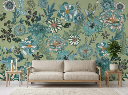 A light beige sofa is centered against a large sage green botanical wallpaper mural adorned with blue and white flowers and hummingbirds.